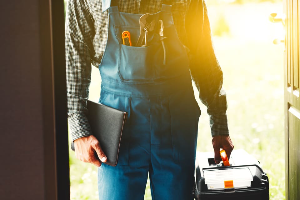 Plombier se présentant à la porte d'entrée en boîte à outils